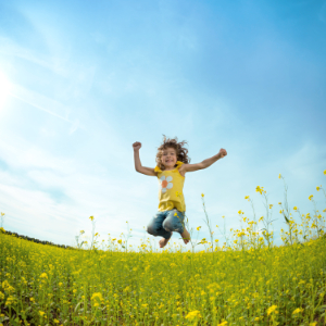 Happy girl jumping on field of yellow flowers