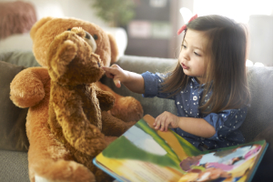 Little girl telling story to stuffed bear